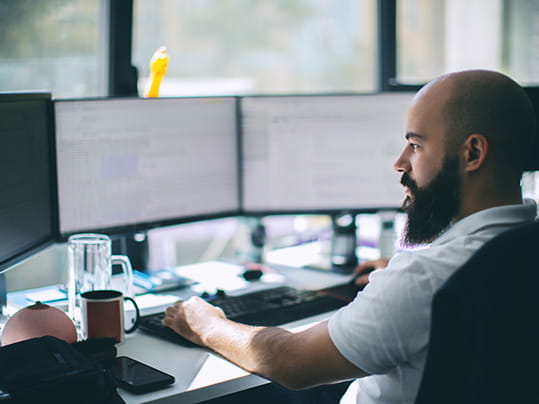 man working on multiple monitors