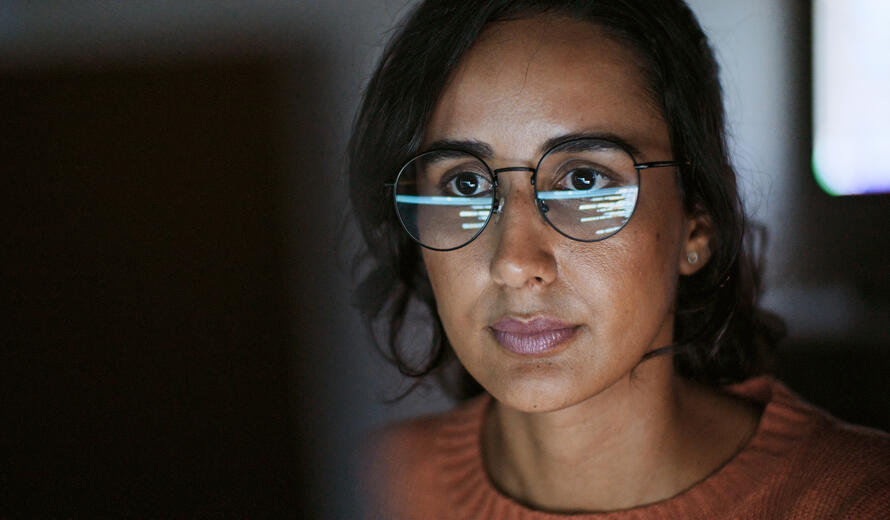 woman with glasses staring at a screen