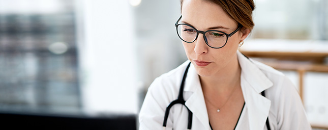 doctor with glasses looking at a computer